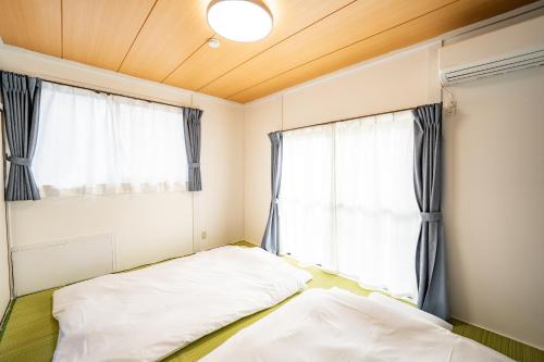 a bedroom with two beds and a window at 貸切温泉付き宿 風蒼 Huua in Kirishima