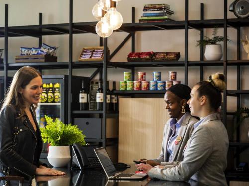 three women standing at a counter in a coffee shop at Aparthotel Adagio London Stratford in London
