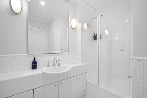 a white bathroom with a sink and a shower at Comfort Apartments Melbourne Central in Melbourne