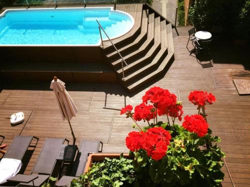 a swimming pool with a bunch of red flowers and stairs at Hotel Dolomiti in Malcesine