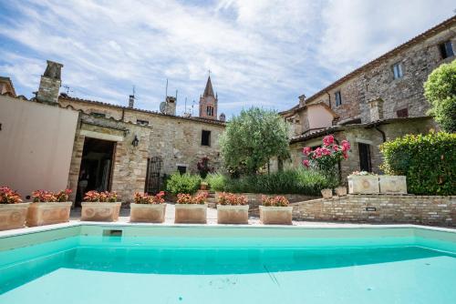 a swimming pool in front of a building with plants at BorgoCuore in Todi