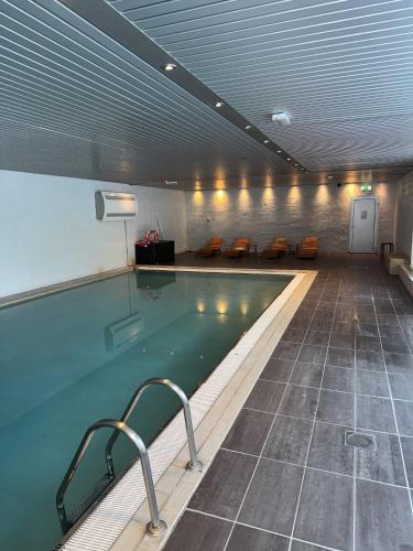 a large swimming pool in a building with chairs at Oppheim Resort - Pool, Sauna & Lake! in Vossevangen