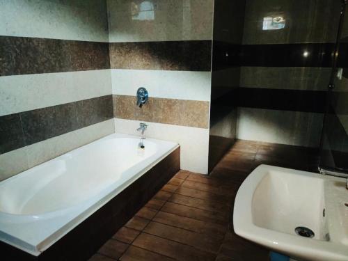 a bathroom with a white tub and a sink at Hotel Mountain Nest in Nārkanda