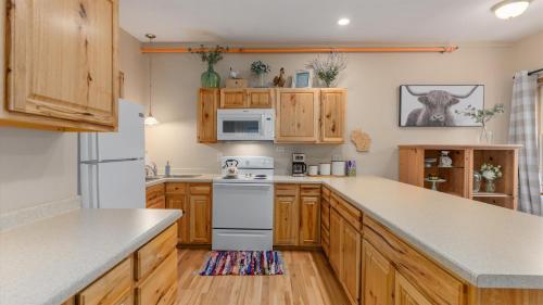 a kitchen with wooden cabinets and a white stove top oven at 3BR Condo Near Lake Pepin w 2 Kitchens - Lantern Condos in Pepin