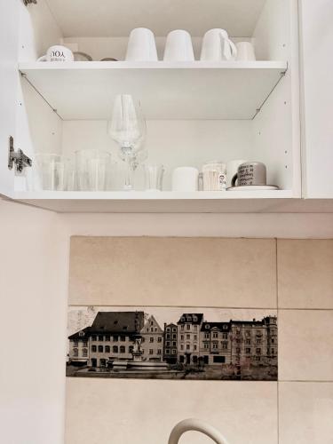 a white shelf with cups and dishes on it at OLD TOWN Palatul Agoston Galgon in Timişoara