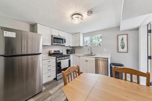 a kitchen with a table and a stainless steel refrigerator at Cozy 2BR Garden Apartment Near Lake Pepin - Daisy in Pepin