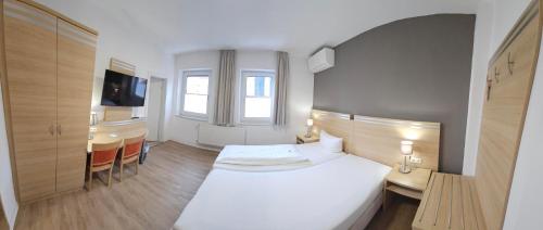 a bedroom with a white bed and a desk and a kitchen at Hotel Altes Weinhaus in Neustadt an der Weinstraße