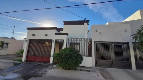 a white house with a red door at Casa centrica y acogedora para tu visita a Hermosillo in Hermosillo