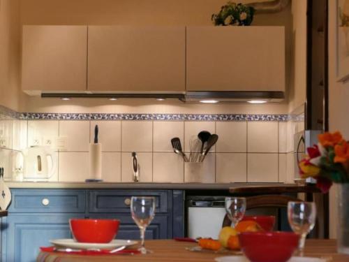 a kitchen with blue cabinets and a table with wine glasses at by Interhome in Louhossoa