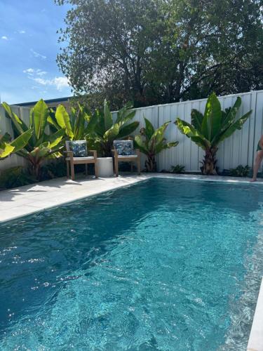a swimming pool with two chairs and a fence at 5 min stroll to the heart Of Huskisson in Huskisson