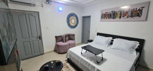 ein Schlafzimmer mit einem Bett, einer Tür und einem Stuhl in der Unterkunft O'sena in Cotonou