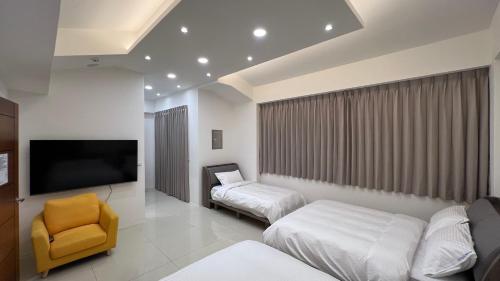 a room with two beds and a tv and a chair at 荷民宿 HO Homestay in Yuanshan