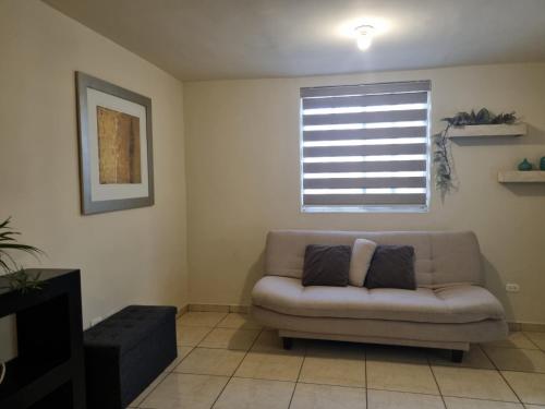 a living room with a couch and a window at Casa centrica y acogedora para tu visita a Hermosillo in Hermosillo