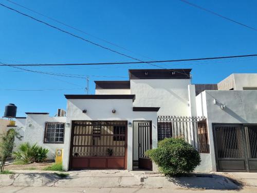 a white house with a red door at Casa centrica y acogedora para tu visita a Hermosillo in Hermosillo