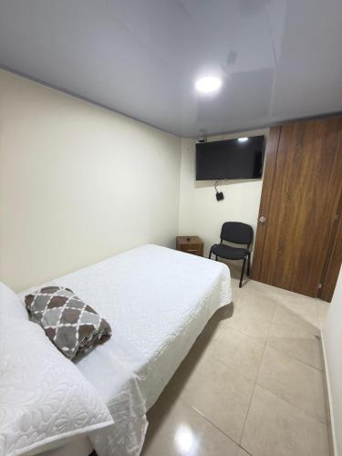 a bedroom with a white bed and a chair at Hotel Plaza de Toros in Manizales