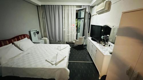 a hotel room with a bed and a television at Sürücü oteli in Milas
