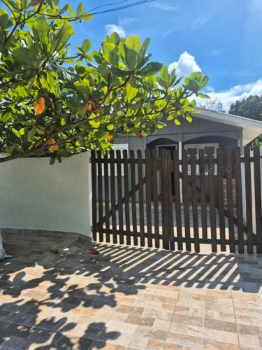a wooden fence in front of a house with an orange tree at Casa Chalé Ilha Comprida in Ilha Comprida