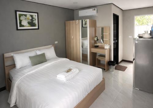 a bedroom with a large white bed and a refrigerator at MBB House in Thalang