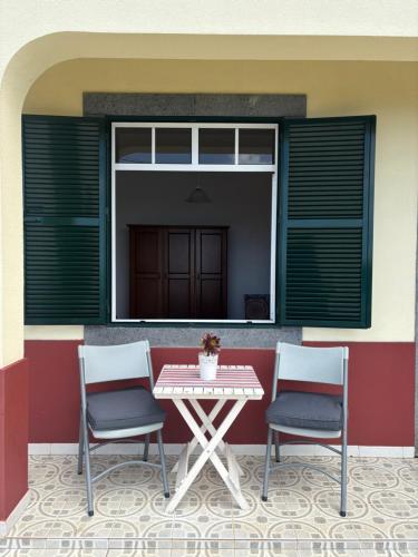 two chairs and a table in front of a building at Casa do Arco in Arco da Calheta