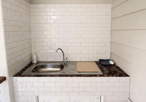 a kitchen with a sink and white tiled walls at MBB House in Thalang