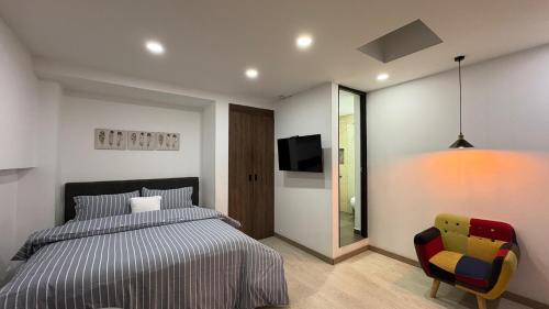 a bedroom with a bed and a tv and a chair at Spacio30 in Bogotá