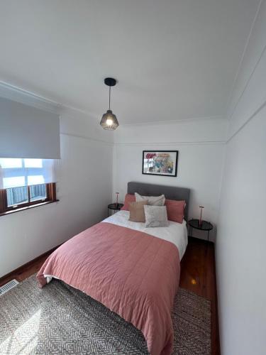 a bedroom with a large bed with a pink blanket at Watson Street Cottage in Albury
