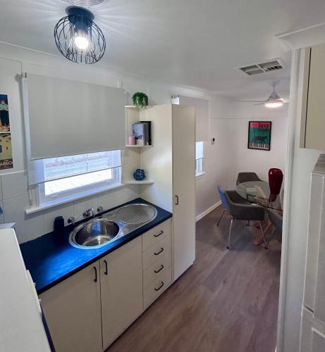 a small kitchen with a sink and a living room at Watson Street Cottage in Albury