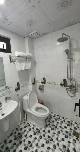 a white bathroom with a toilet and a sink at Seagull Hotel in Cat Ba