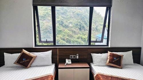 two beds in a room with two large windows at Seagull Hotel in Cat Ba