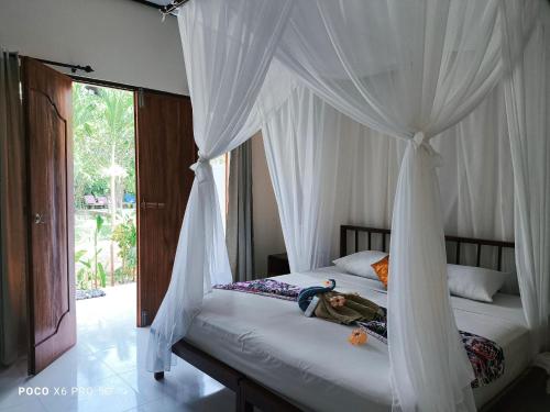 a bedroom with two beds with white drapes at Mango Moon in Pemuteran