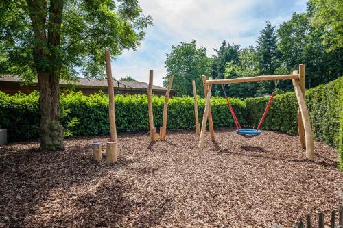 a playground with two swings and a tree at Bungalowpark Het Verscholen Dorp in Harderwijk