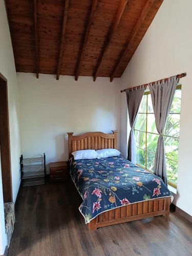 a bedroom with a bed with a floral bedspread and a window at Moss in Colombia