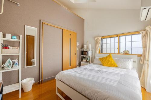 a bedroom with a large white bed with yellow pillows at Rooms箱崎 in Fukuoka