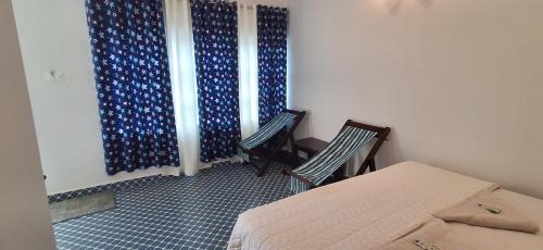 a room with two chairs and a bed and curtains at Mudra beach villa Gokarna in Gokarna