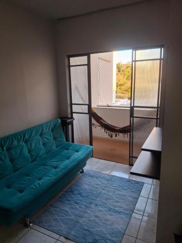 a living room with a green couch and a hammock at Aconchego II in Juiz de Fora
