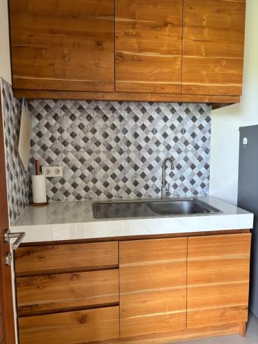 a kitchen with wooden cabinets and a sink at Private Studio Near Kedungu Beach Cozy & Affordable in Tanah Lot
