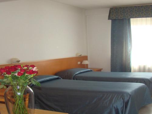 1 dormitorio con 2 camas y un jarrón de rosas rojas en Hotel da Rosanna, en Attigliano
