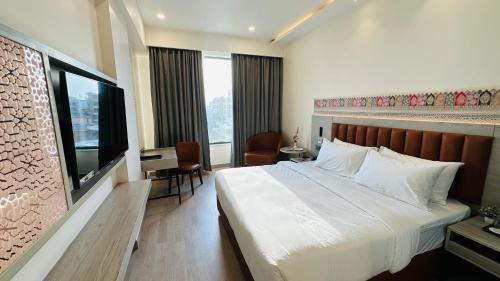 a bedroom with a bed and a desk and a television at Regenta Central Jaipur in Jaipur