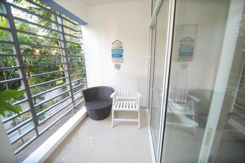a balcony with two white chairs and a window at franchecis hostal cerca del mar in Juan Dolio