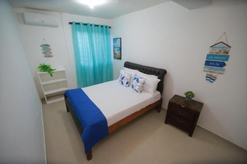 a small bedroom with a bed and a blue curtain at franchecis hostal cerca del mar in Juan Dolio