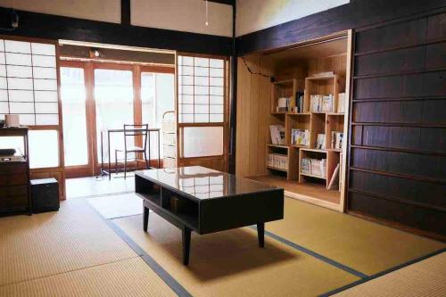 a living room with a table and a book shelf at Rebe東吉野 in Higashiyoshino