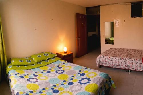 a bedroom with a bed with a comforter on it at Hotel mi casita in Bogotá