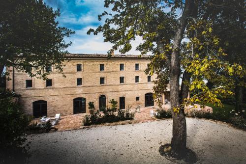 a large brick building with a tree in front of it at Villa Anitori Prestige Relais & Spa in Loro Piceno