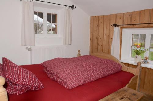 a red bed in a bedroom with a window at Windshausen 84 in Nußdorf am Inn