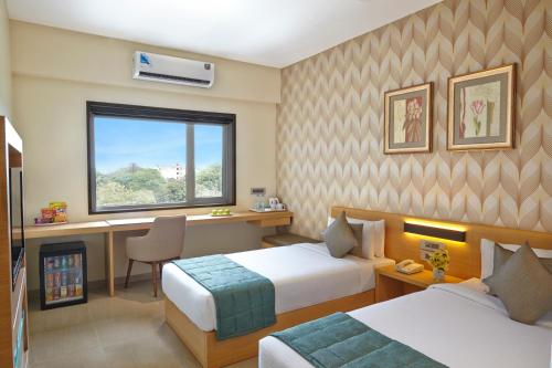Habitación de hotel con 2 camas y ventana en Click Hotel, Junagadh en Jūnāgadh
