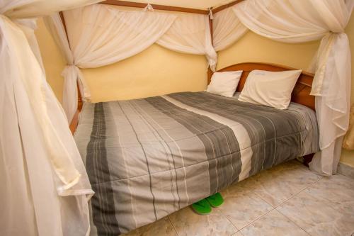 1 dormitorio con cama con dosel y cortinas blancas en Hotel Nomad, en Athi River