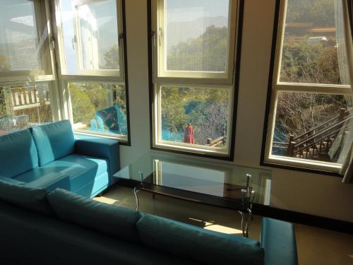 a living room with a blue couch and windows at Natural Residence B&B in Taian