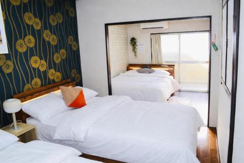 a hotel room with three beds and a mirror at Maison du Skytree Tokyo in Tokyo