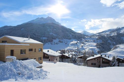 a village covered in snow with a mountain in the background at Ferienwohnung Aviez Savognin in Savognin