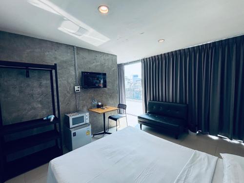 a bedroom with a bed and a couch and a desk at Udomsuk Inn & Cafe - BTS Udomsuk in Bangkok